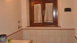 Et badeværelse med toilet, vask og et vindue med gardiner.