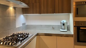 Een moderne keuken met een gasfornuis, een ingebouwde magnetron en houten keukenkastjes.