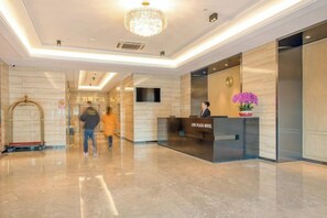Un hall d’hôtel comprenant un comptoir d’accueil, un lustre et un téléviseur fixé au mur.