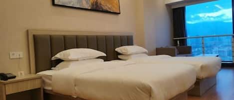 A hotel room with two beds, a nightstand, a painting on the wall, and a large window with a city view.