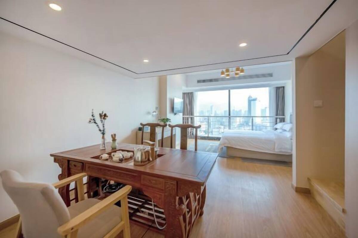 Ein modernes Hotelzimmer mit einem Holzbüro, einem Bett und einem großen Fenster mit Blick auf die Stadt.