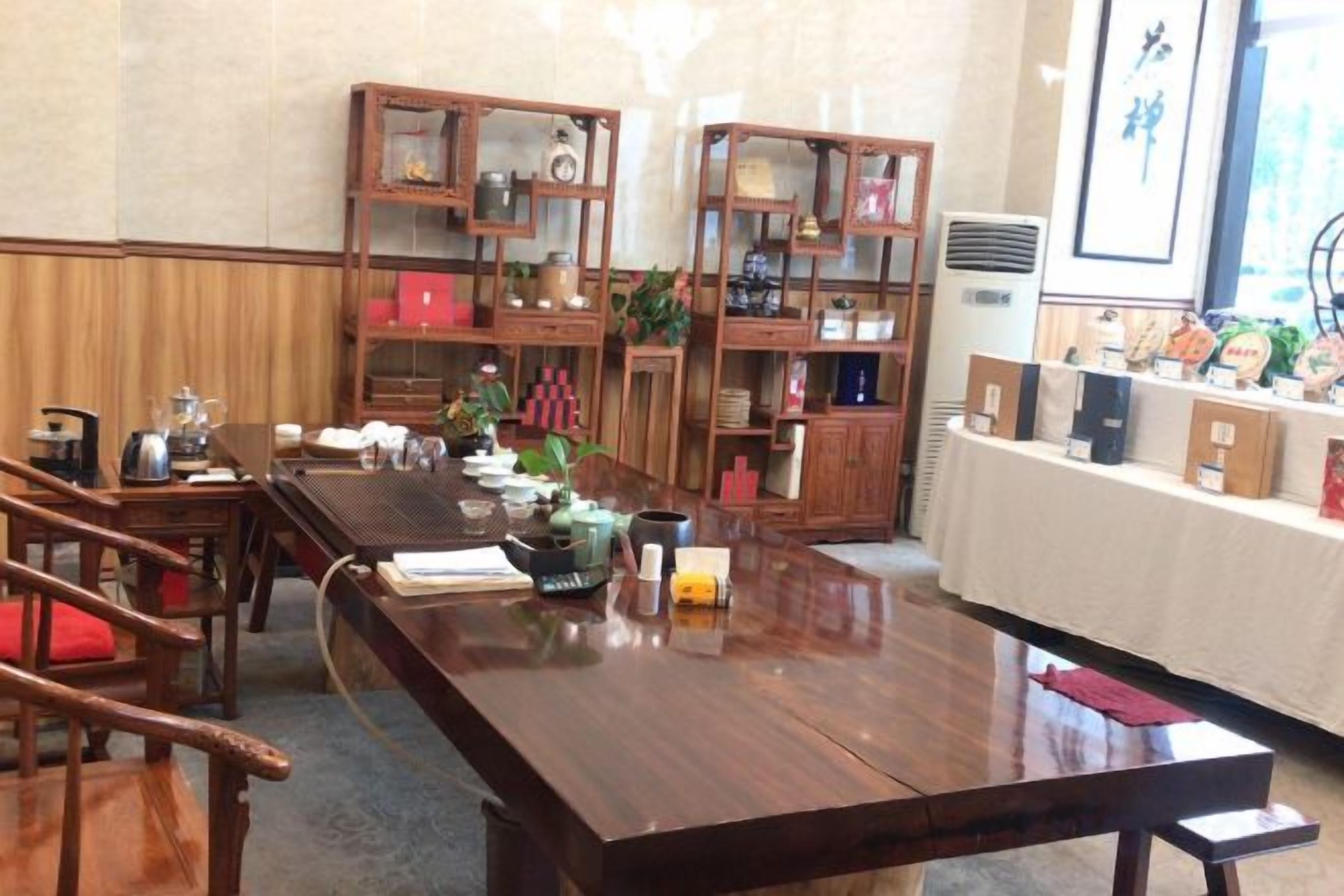 A wooden dining table with chairs, a bookshelf, and a small plant.