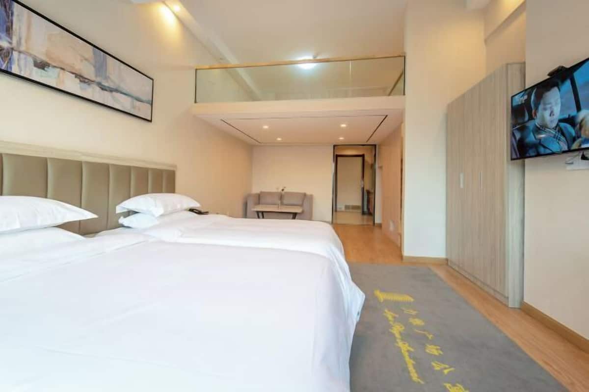 Ein modernes Hotelzimmer mit einem großen Bett, einer kleinen Sitzecke und einem an der Wand befestigten Fernseher.