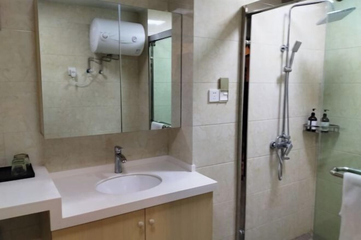 A bathroom with a sink, mirror, and a glass-enclosed shower area.