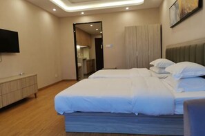 A bedroom with a bed, a TV, a wardrobe, and a mirror.