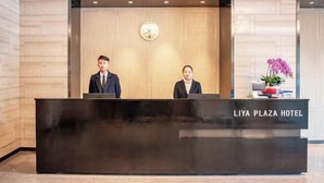 Mostrador de recepción en el HOTEL LIYA PLAZA, con un reloj encima.