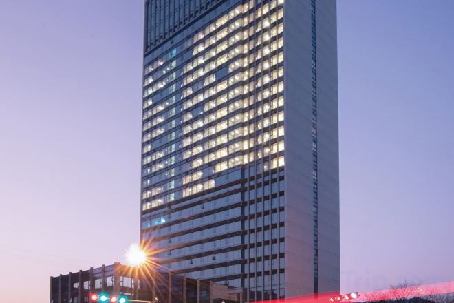 Un edificio alto con numerosas ventanas, probablemente un hotel o edificio de oficinas, con un cielo despejado al fondo.