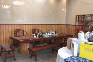 Un comedor con una mesa de madera, sillas, un banco y una estantería con diversos objetos.