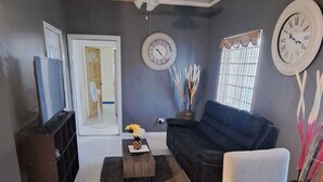 A living room with a sofa, a coffee table, a TV, and two clocks on the wall. - The Cabin Retreat (Bonne Terre)