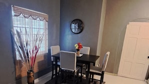 A living room with a dining area, a clock on the wall, and a window with blinds. - The Cabin Retreat (Bonne Terre)
