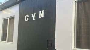 A building with a black door labeled "GYM" and a white exterior. - The Cabin Retreat (Bonne Terre)