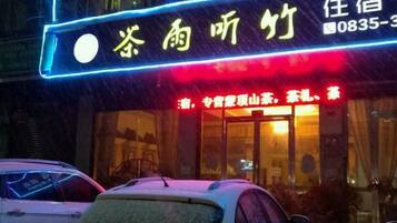 A hotel with a neon sign, a visible entrance, and a car parked in front.