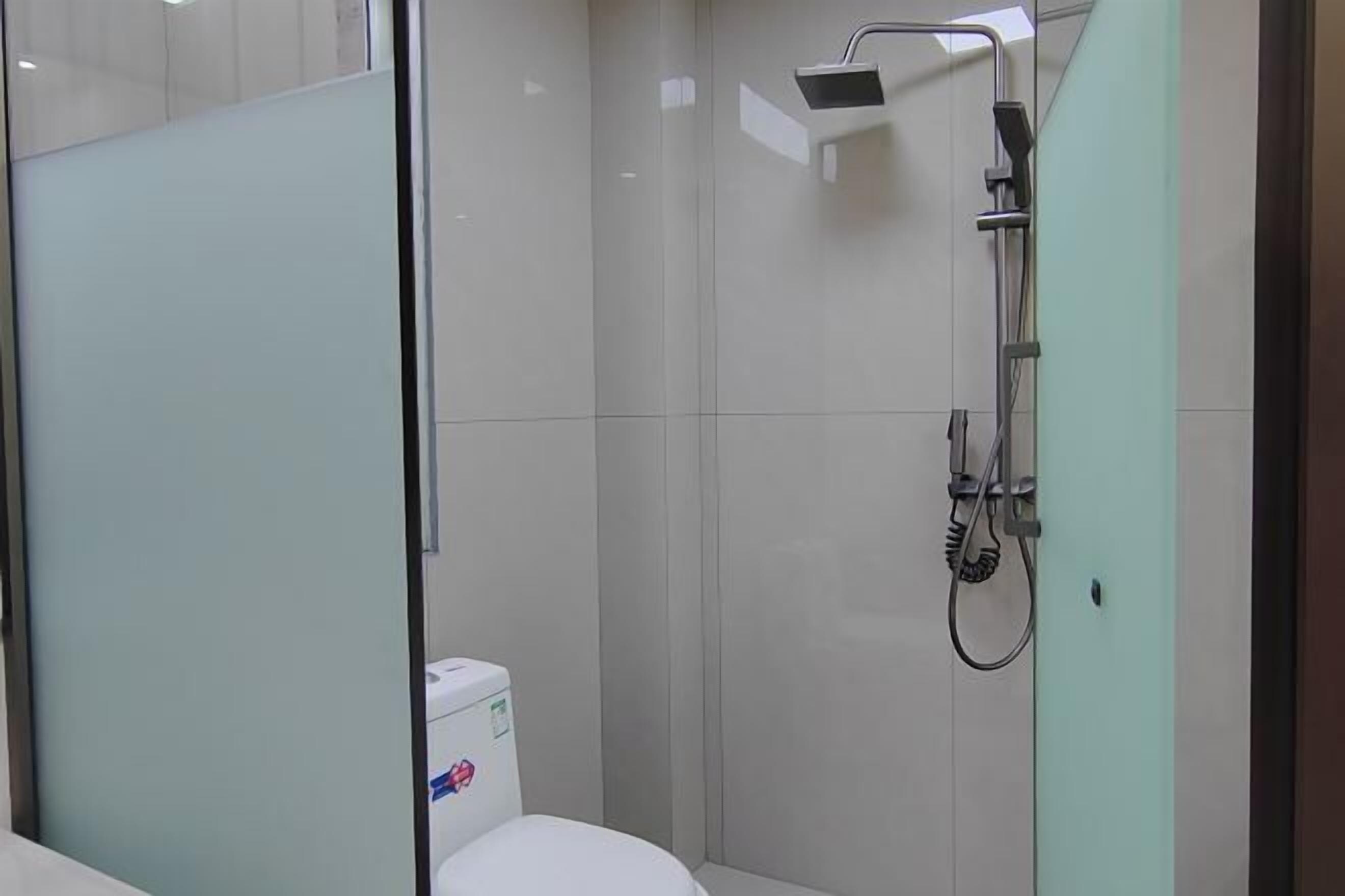 Un baño moderno con mampara de vidrio, ducha e inodoro.