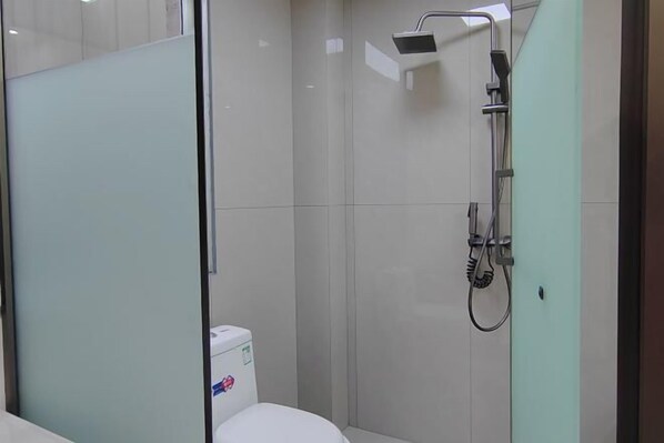 Un baño moderno con mampara de vidrio, ducha e inodoro.