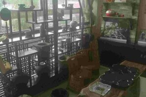 A kitchen with various cooking utensils and appliances, a dining area with a table and chairs, and a view of the outdoors through a window. - Chayu Tinzhu Hotel (Ya'an)