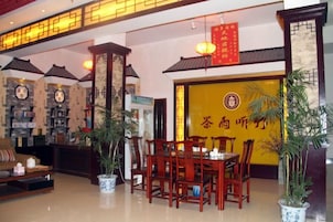 Interior de un restaurante chino tradicional, con zona de comedor, mostrador de recepción y una pared con caracteres chinos.