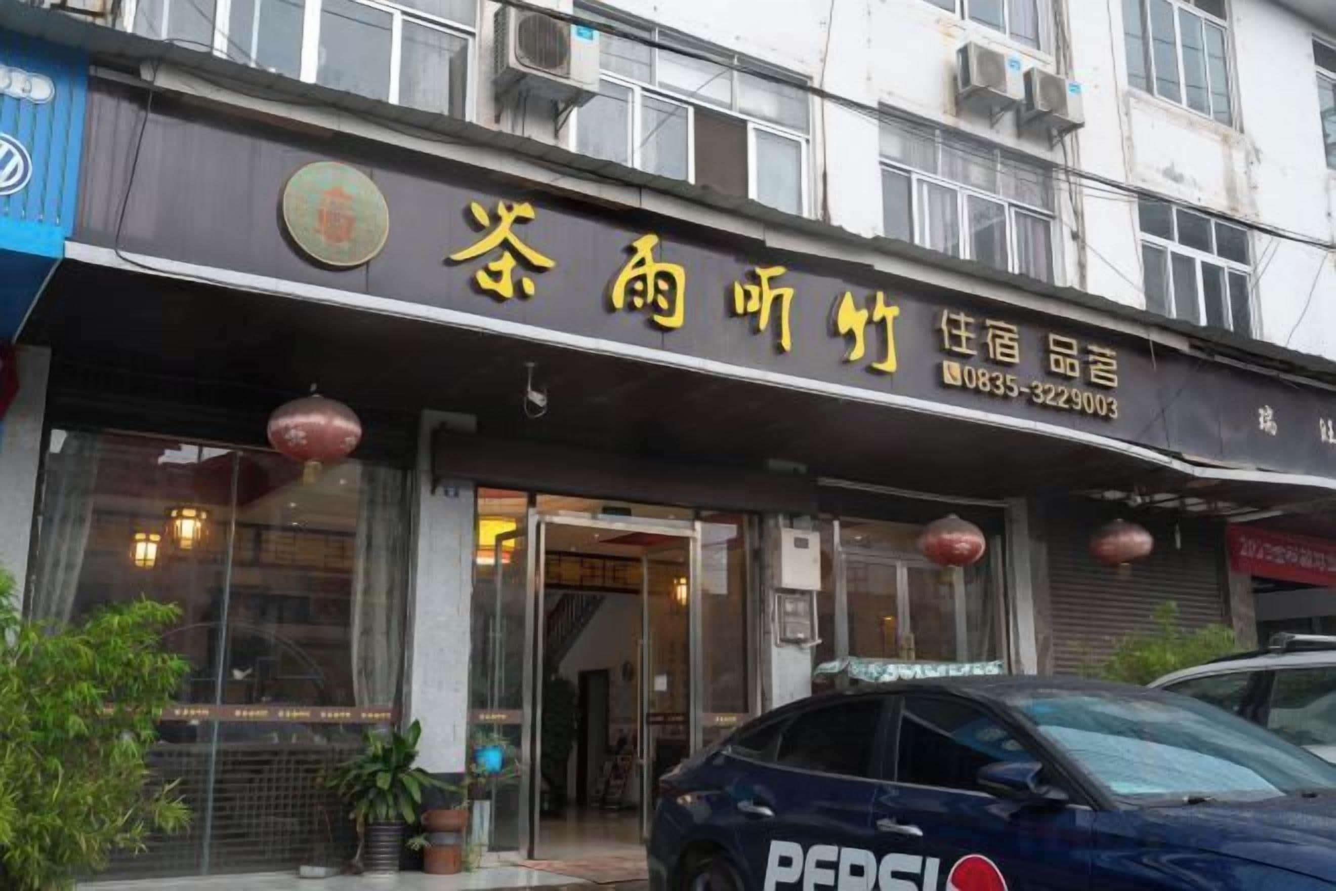 A hotel with a signboard displaying its name and contact information.