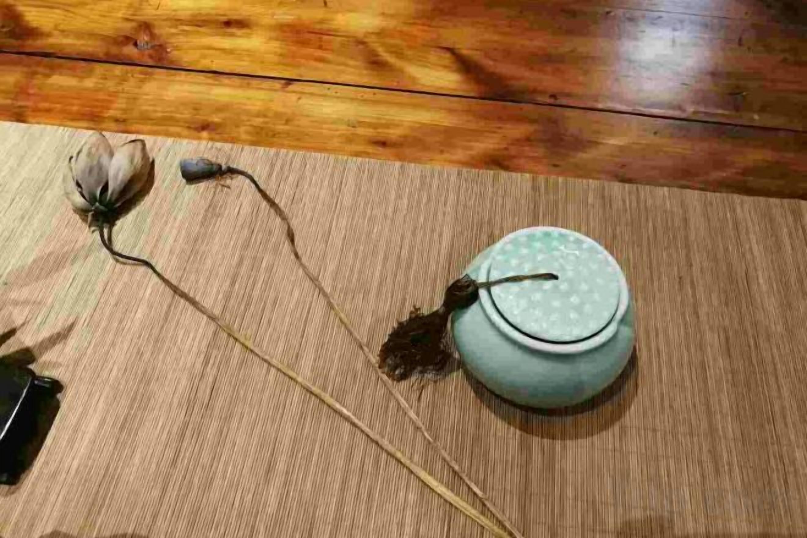 A wooden floor with a ceramic pot and dried flowers.