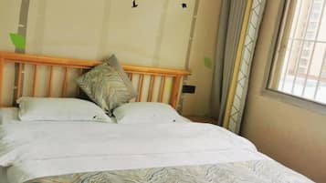 Una cama con cabecera de madera, dos almohadas y una colcha estampada.