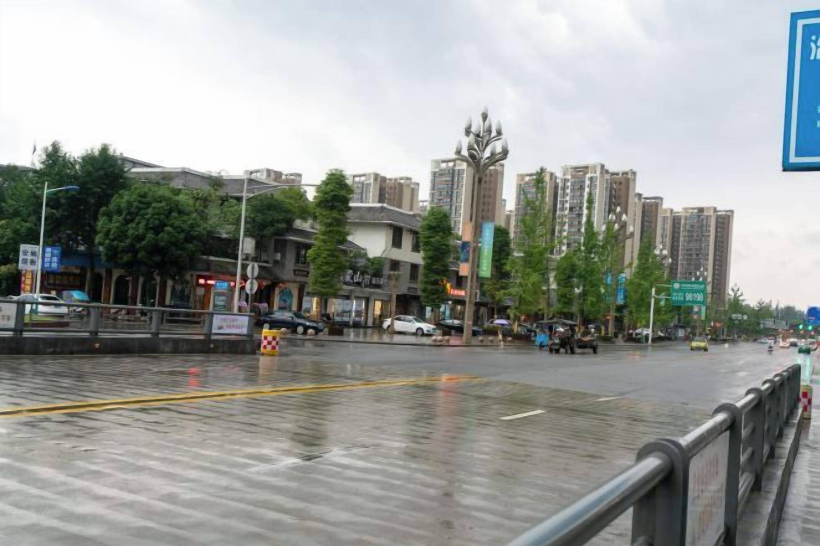Una calle urbana con edificios, un paso de peatones y asfalto mojado.
