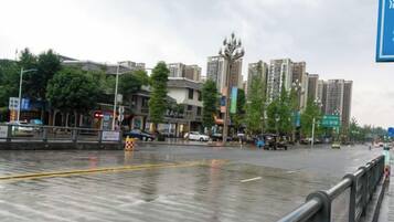 Una calle urbana con edificios, un paso de peatones y asfalto mojado.