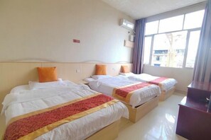 Habitación de hotel con dos camas, una ventana con cortinas, un aire acondicionado y un escritorio.