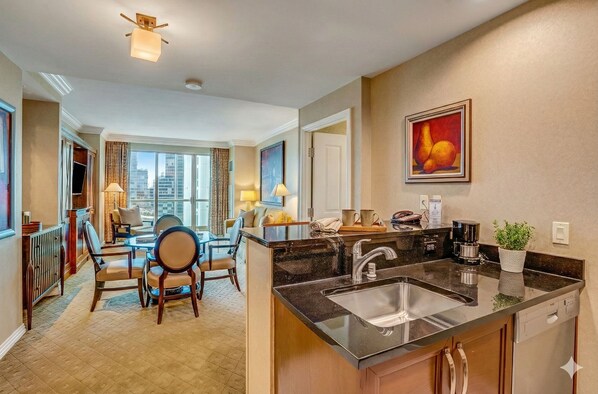 Une chambre d’hôtel moderne dotée d’un coin cuisine, d’un espace repas et offrant une vue sur la ville.