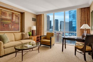 Una habitación de hotel con un ventanal grande, un sofá, una silla, un escritorio y una lámpara.