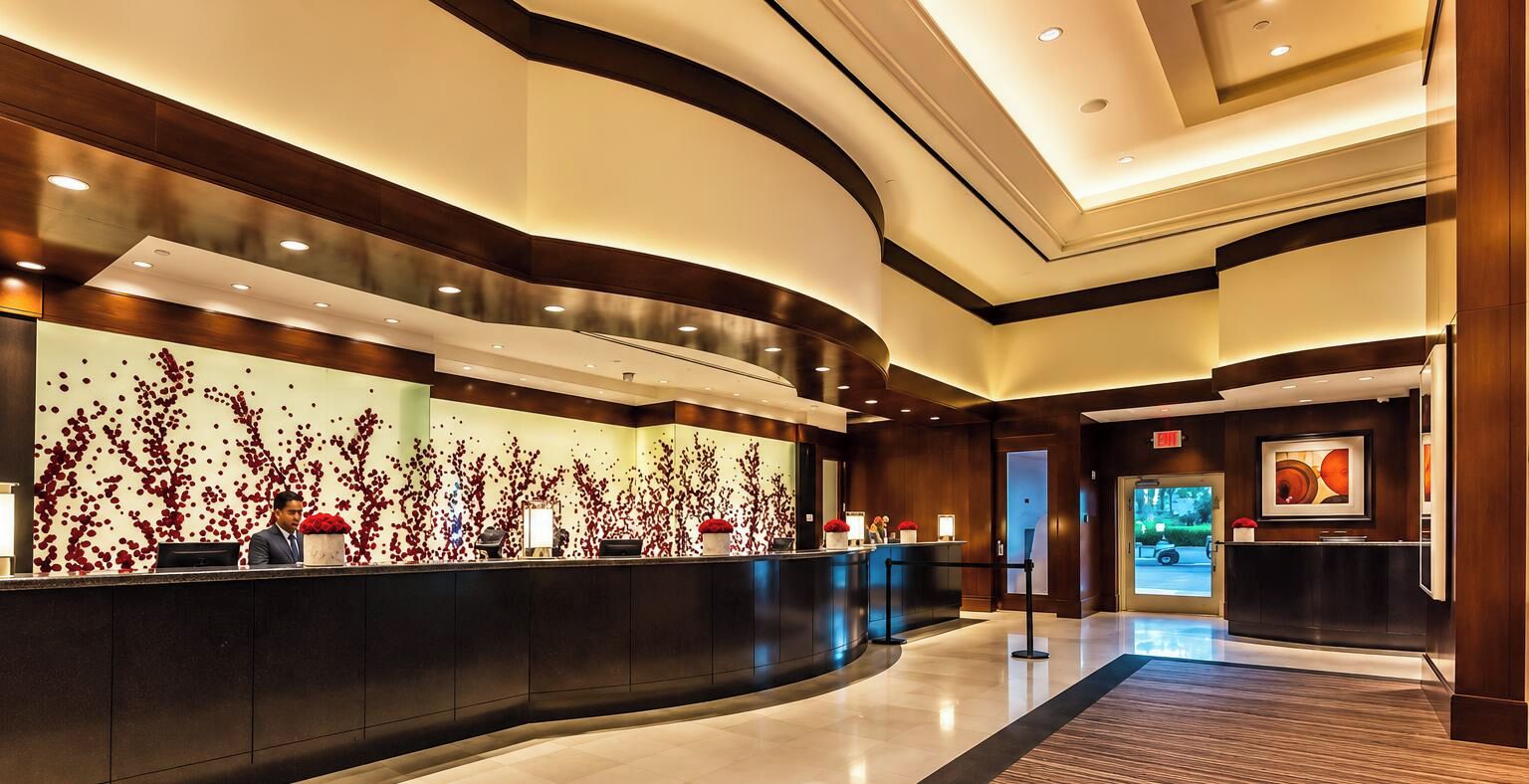 Eine moderne Hotelhalle mit einer gebogenen Rezeption, einer großen Wand mit floralem rotem Muster und einem gerahmten Kunstwerk.