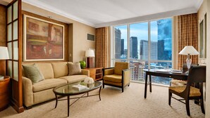 A spacious living room with a large window offering a city view, a comfortable sofa, a coffee table, and a dining area with a table and chairs. - MGM Signature | 32nd Floor Studio | City View | No Resort Fee (LAS VEGAS)