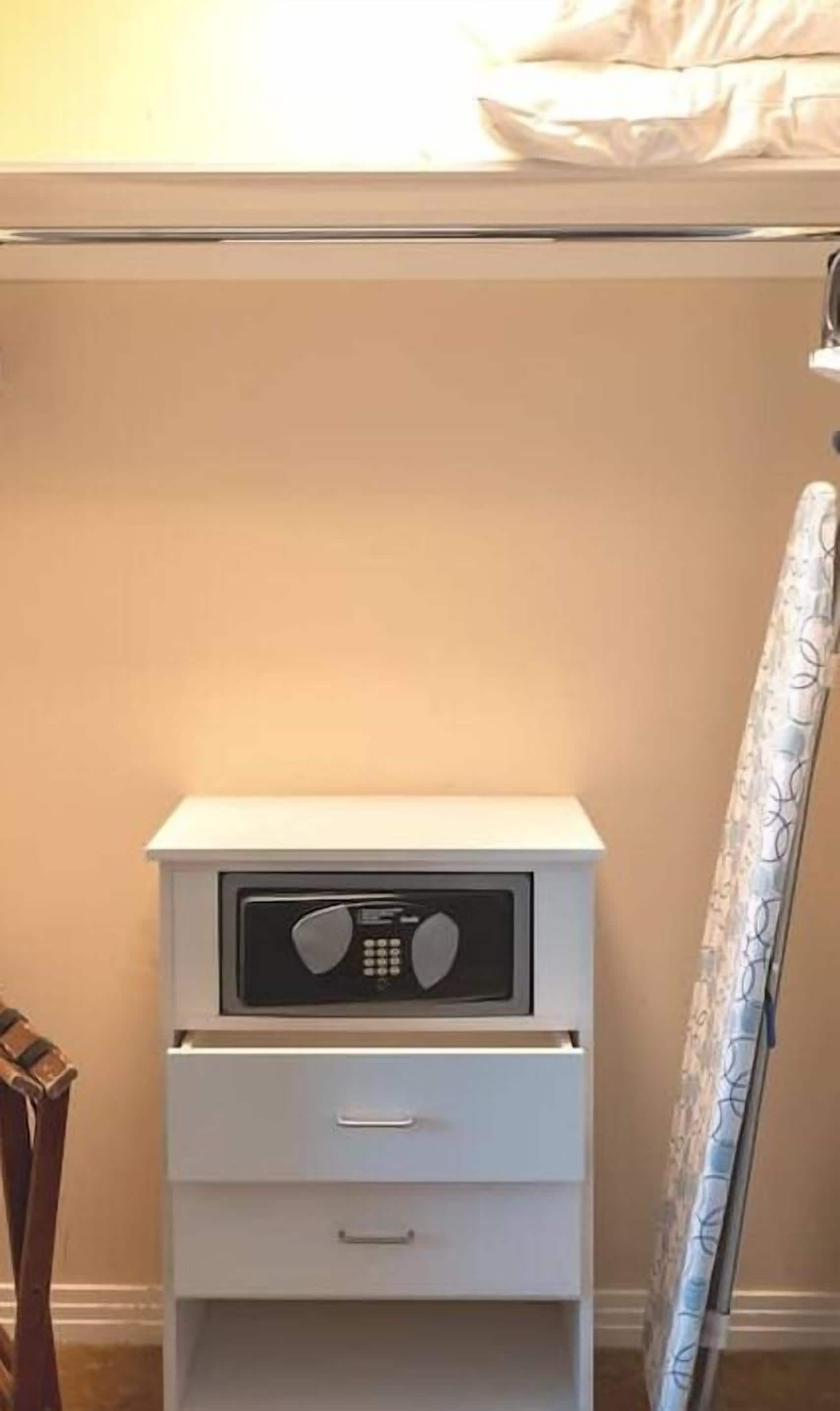 Una mesita de noche blanca con radio incorporada y un cajón.