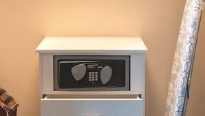 Una mesita de noche blanca con radio incorporada y un cajón.