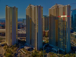 A high-rise building with multiple floors, surrounded by palm trees and other buildings.