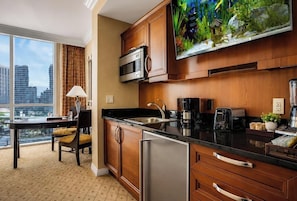 A modern kitchen with a large window, a flat-screen TV, and a city view.
