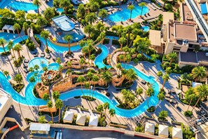 Vista aérea de un resort con varias piscinas, palmeras y zonas de descanso.