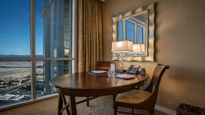 A hotel room with a large window offering a city view, a round table with a lamp, a chair, and a telephone. - MGM Signature | 32nd Floor Studio | City View | No Resort Fee (LAS VEGAS)