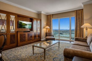 A hotel room with a large window, a flat-screen TV, a sofa, a coffee table, and a patterned rug. - MGM Signature | 32nd Floor 2BR Combo | City View & Balcony | No Resort Fee (LAS VEGAS)