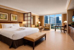 Habitación de hotel con una cama grande, un escritorio, una silla y vistas a la ciudad.