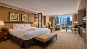 Habitación de hotel con una cama grande, un escritorio, una silla y vistas a la ciudad.