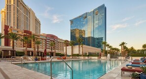 Ein Hotelpoolbereich mit freiem Blick auf die Architektur des Hotels, darunter ein modernes Glasgebäude und eine klassische Fassade.
