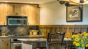 Una cocina rústica con armarios de madera, microondas, estufa y una mesa de comedor con sillas.