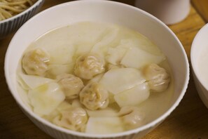 A bowl of soup with dumplings and noodles. - Blossom Hill Hotel Ningbo Hanling (Ningbo)