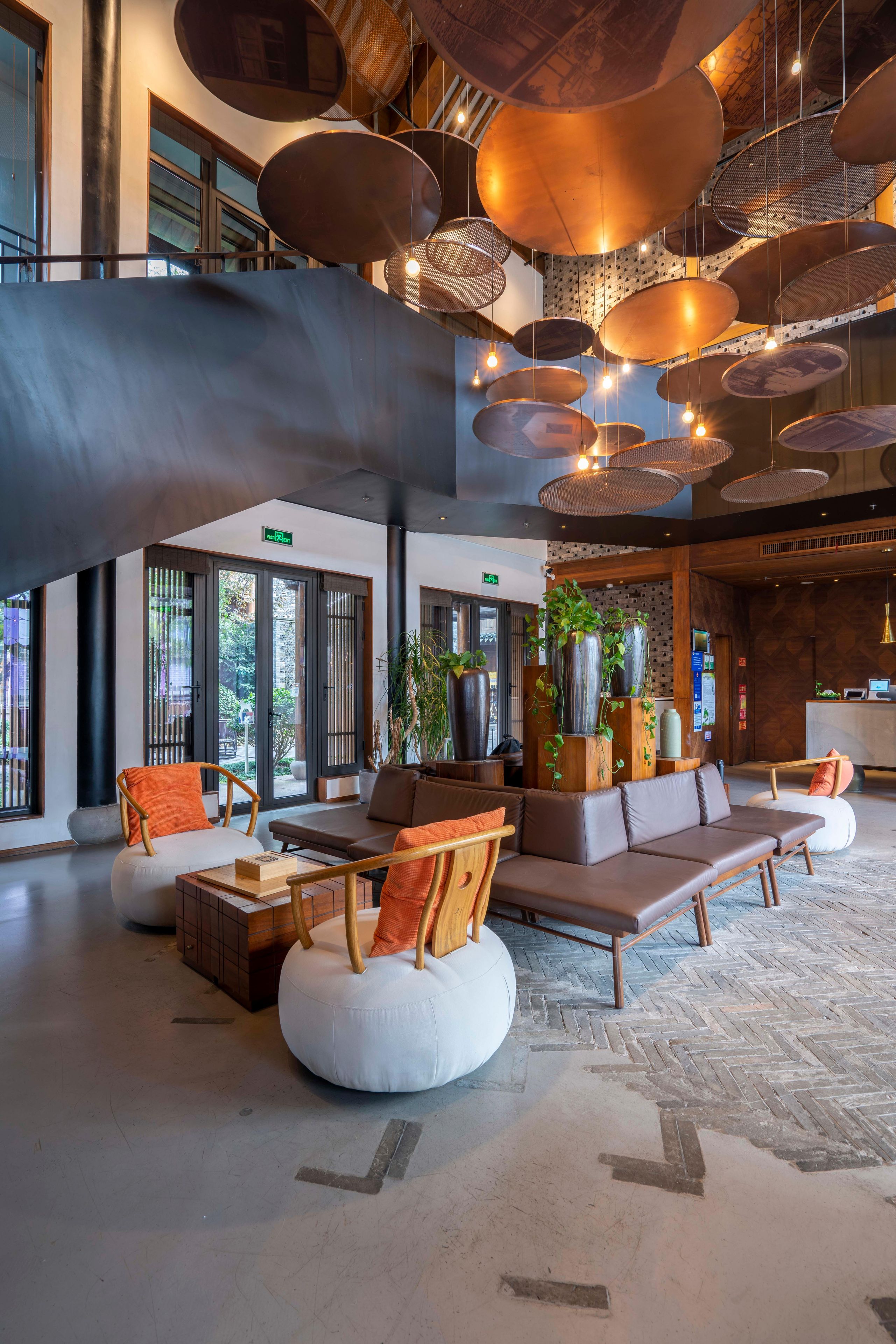 A spacious lobby with modern seating, large windows, and a unique ceiling design.