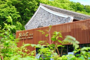 A traditional building with a stone roof and a wooden structure in the foreground. - Blossom Hill Hotel Ningbo Hanling (Ningbo)