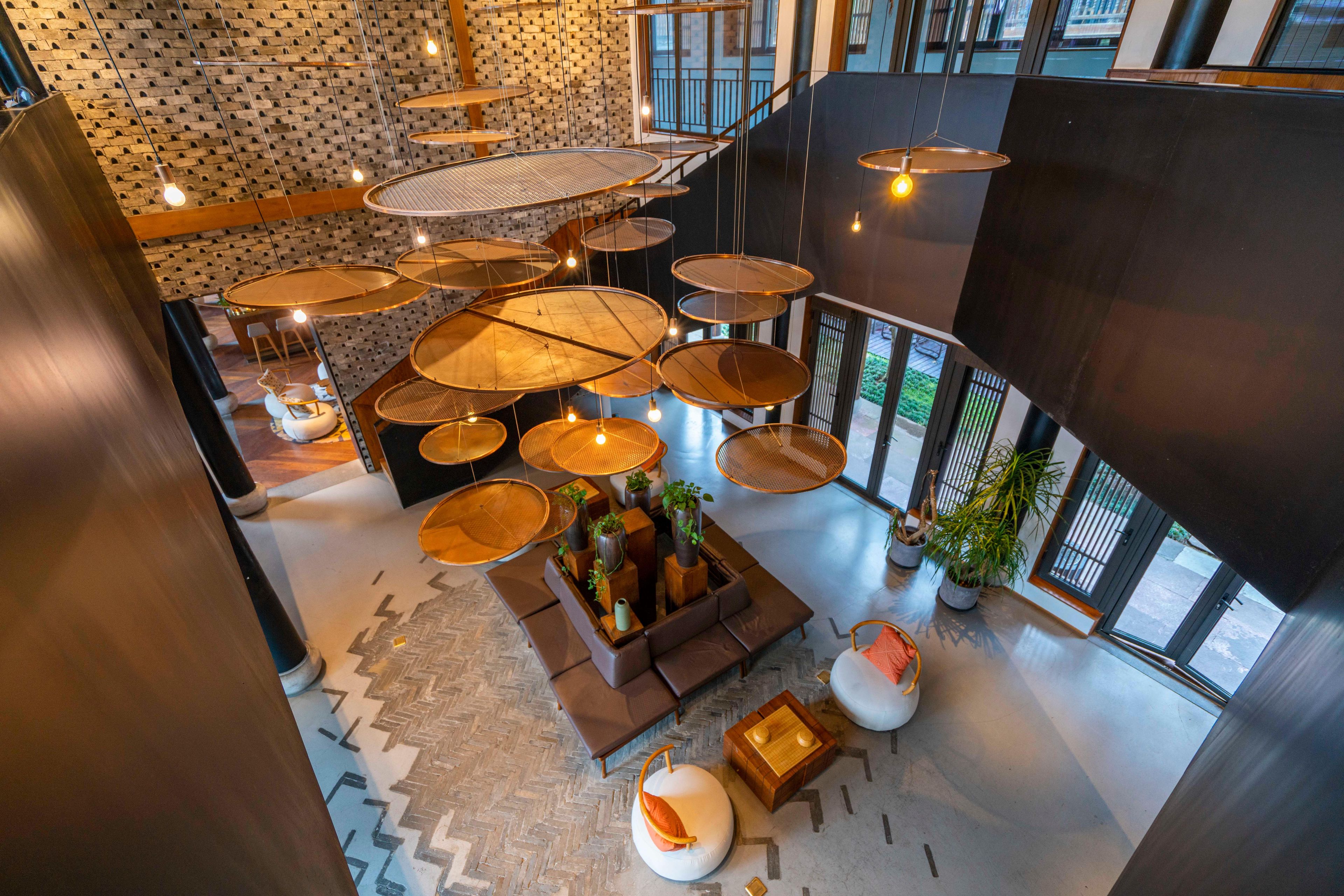 A spacious lobby with multiple seating areas, a central coffee table, and a staircase leading to an upper level.