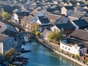 A traditional town with narrow streets, historic buildings, and a canal with boats. - Blossom Hill Hotel Ningbo Hanling (Ningbo)