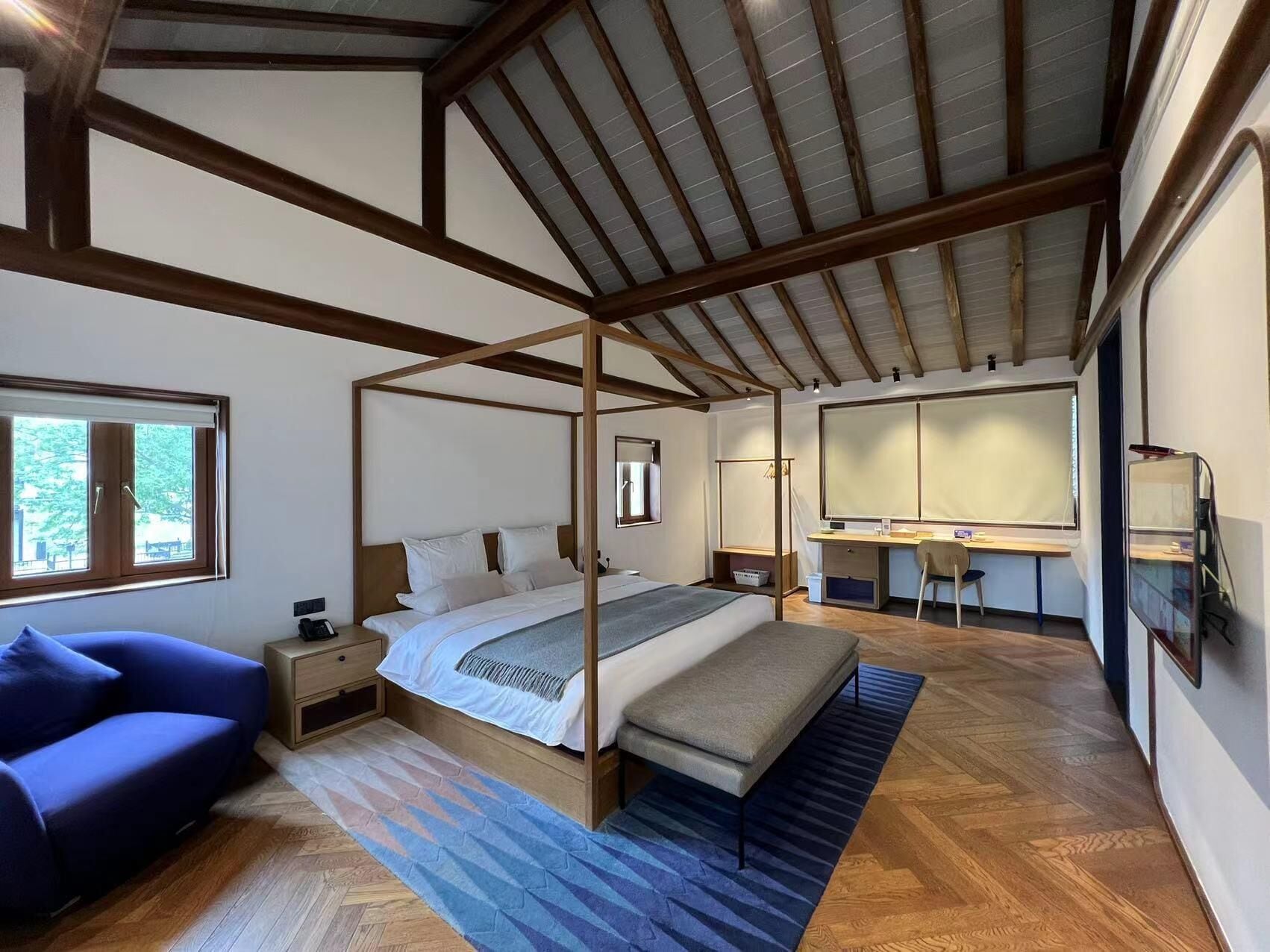 A bedroom with a four-poster bed, a desk, a chair, and a sofa.