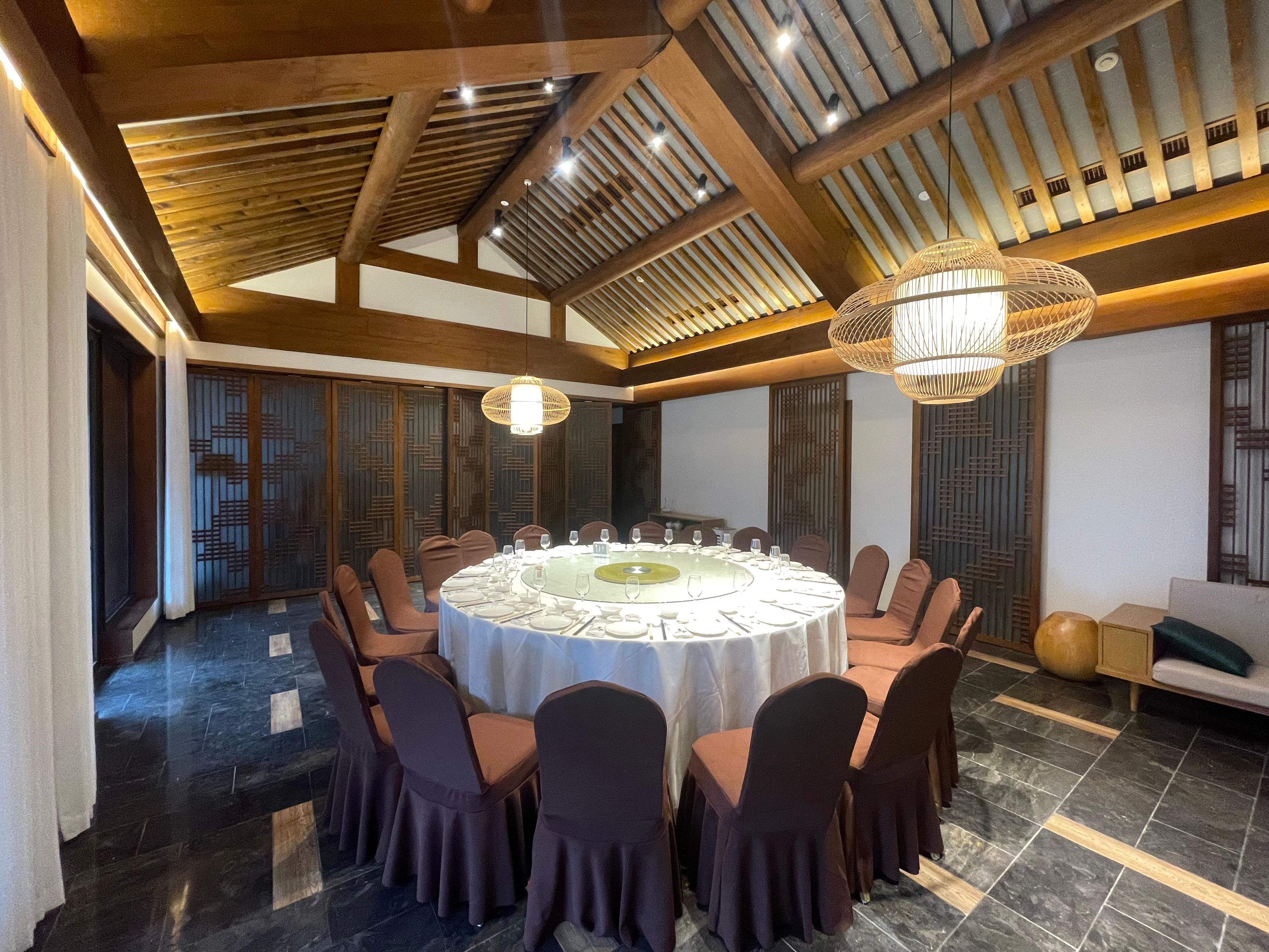 A conference room with a round table, chairs, and a chandelier.