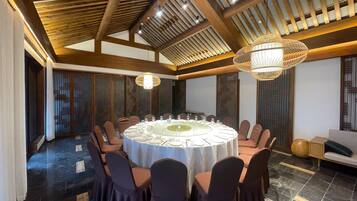 A conference room with a round table, chairs, and a chandelier.