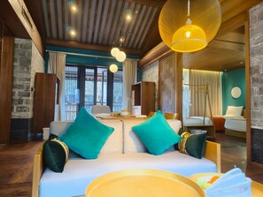 A modern hotel room with a wooden ceiling, a large window, a sofa with teal cushions, and a hanging lamp. - Blossom Hill Hotel Ningbo Hanling (Ningbo)